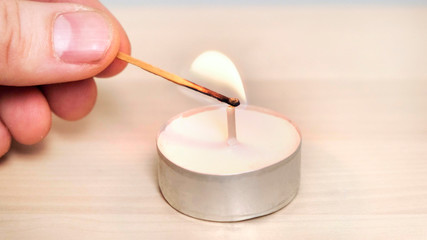 Burn a candle with a wooden match. Close up.