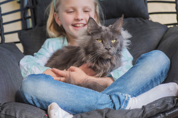 Summertime fun. Child playing with cat at garden
