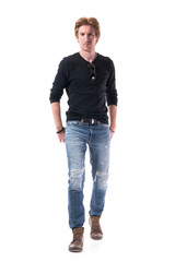 Front view of stylish modern young man walking and approaching to camera with hands in back...