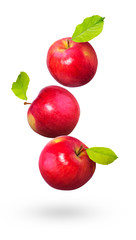 Red apples with green leaves fly on a white background.