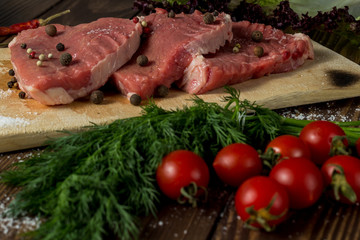 raw meat on a cutting board. beef steak with herbs, cherry tomatoes, onions