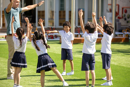 Foreign teacher and children playing in kindergarten playground