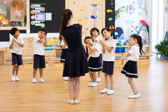 Teacher teaching children dancing in classroom