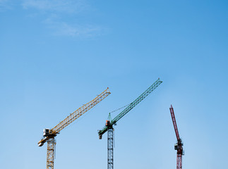 Boom cranes on a background of cloudy cloudy sky. Construction cranes on blue sky background.