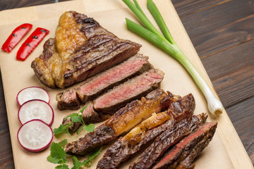 Marbled beef steak medium rare with vegetables on wooden cutting board. Fresh grilled meat.