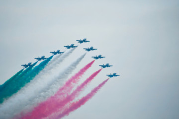 Military aircraft drawing an arrow Italian flag in the cloudy sky