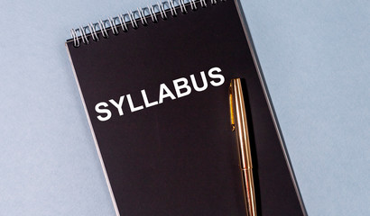 Syllabus word text on black notebook with golden pen on blue table. Education concept.