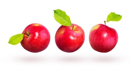 Red apples with green leaves fly on a white background.