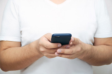 A person is holding a phone and tapping the screen on a white background with copy space. Concept of lifestyle business and Internet technologies in the office