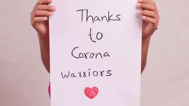Kid in medical mask showing thank you corona warriors banner - Concept of gratitude for coronavirus or covid-19 healthcare and all frontliners.