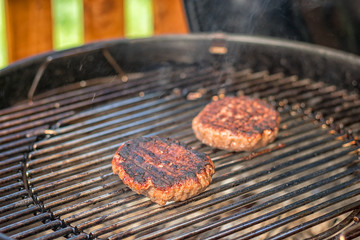 grilled meat - two burnt burgers on an outdoor grill