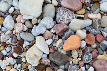 Pile of different smooth stones on the seashore.
