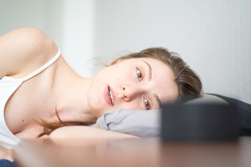 Fototapeta premium A young woman with insomnia asks the voice assistant to include sleepy music. Smart portable speaker helps you fall asleep