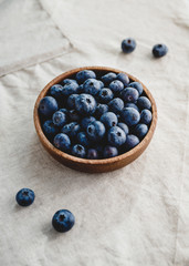 Fresh blueberry in a wooden bowl on a linen light cloth. Healthy eating and Summer concept.