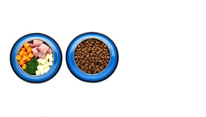 Two blue bowls with dry food for animals and with various ingredients carrot zucchini broccoli meat of healthy food . Dog food concept. Top view. Copy space