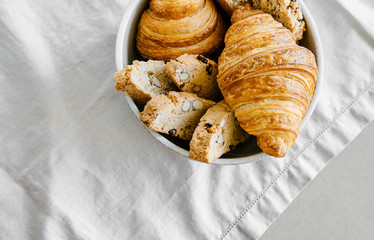 Freshly baked classic croissants and almond biscottis on linen light background. Breakfast food concept. 