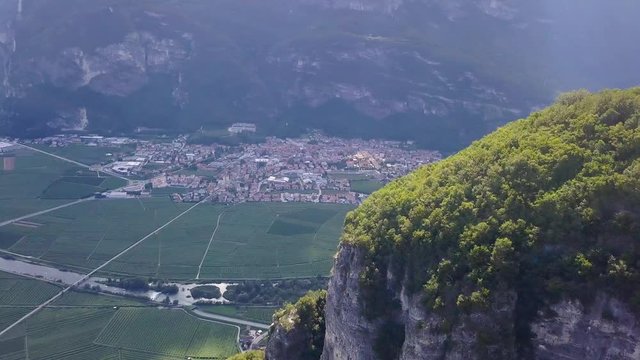 Aerial view of a village in a mountainous valley in Trentino, Northern Italy. Cinematic Drone reveal of lush, green mountains in Trentino, Italy. Mezzocorona in the Rotaliana Plain