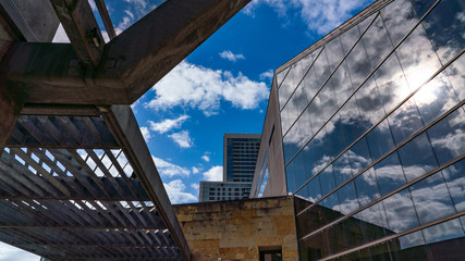 Looking up at a dramatic blue and white sky, framed by architectural steel lines and mirrored windows. © Dawn