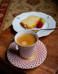 A warm and cozy afternoon with coffee in Hungarian hand-painted 'Herend' porcelain cup with cake and vintage Persian carpet in the background 