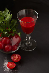 The Fresh tomato juice with the young herbs. The tasty vitamin drink on a the dark background
