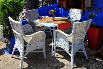 Fototapeta na wymiar View of the chairs near one of the cafe in Chefchaouen, Morocco. The city, also known as Chaouen is noted for its buildings in shades of blue and that makes Chefchaouen very attractive to visitors.