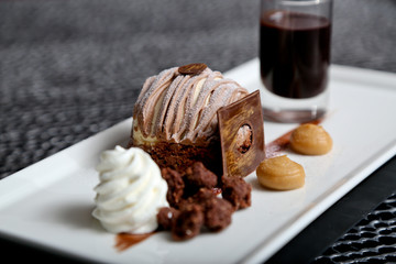 Chocolate and caramel dessert with ice cream and short of espresso on a white plate, side view. Chocolate brownie with vanilla ice cream. Luxurious dessert with brownie, vanilla ice-cream