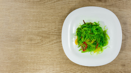 Asian style salad with cellophane noodles, sweet pepper and carrots in white plate over light background. Top view, copy space