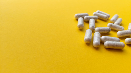 White pills on yellow background. Simple flat lay with pastel texture and copy space. Medical concept. Stock photo.