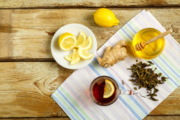 Cup of tea with lemon honey ginger and sprinkled tea on the table.