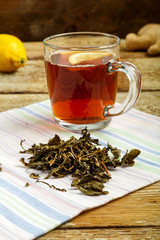Cup of tea with lemon honey ginger and sprinkled tea on the table.