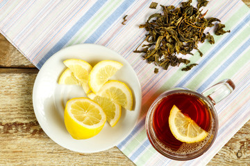 A cup of tea with lemon honey ginger and sprinkled tea on a table on a napkin.