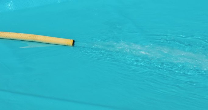 water runs from a yellow hose to a blue pool