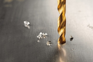 metal drill bit make holes in steel billet on industrial drilling machine with shavings. Metal work...
