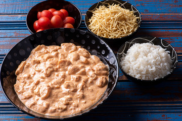 Chicken stroganoff accompanied with rice, salad and potato straw