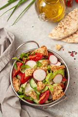 Traditional fattoush salad on a plate with pita croutons, cucumber, tomato,radish and herbs