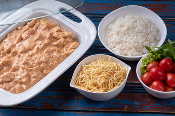 Chicken stroganoff accompanied with rice, salad and potato straw