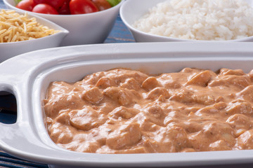 Chicken stroganoff accompanied with rice, salad and potato straw