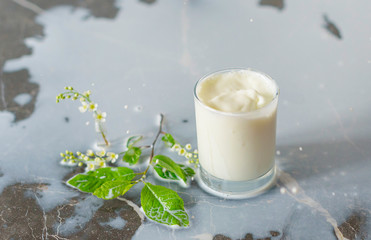 a splash of fresh milk in a glass on dark background with white cherry branch