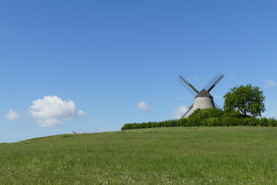 traditional windmill on a hill against blue sky with one little cloud