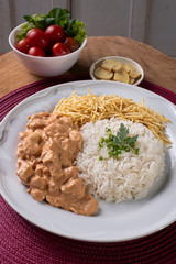 Chicken stroganoff accompanied with rice, salad and potato straw
