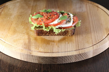 Sandwich with tomato and cheese on a wooden plate