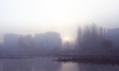 Fototapeta na wymiar Foggy winter morning at urban riverside