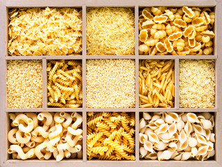 Different types of italian uncooked pasta in wooden box, whole wheat pasta, pasta, spaghetti, noodles, tagliatelle. Top view.