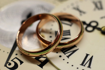 Two wedding rings and a watch with Roman numerals, macro