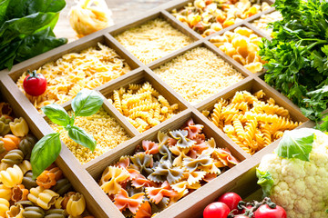 Different types of italian uncooked pasta in wooden box, whole wheat pasta, pasta, spaghetti, noodles, tagliatelle. Top view.