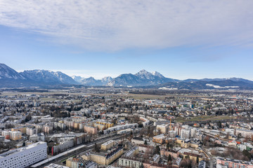 Aerial drone shot view of Salzburg aiglhof station with view of snowy Eastern Bavarian Alps mountain ridge