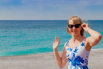 Saying hello. Young woman waving to someone on the Promenade des Anglais. Nice. France.