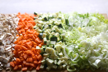 Chopped mushroom, carrot, zucchini and leek on a cutting board. Selective focus.