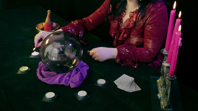 The fortuneteller in the magic salon lights candles on the table