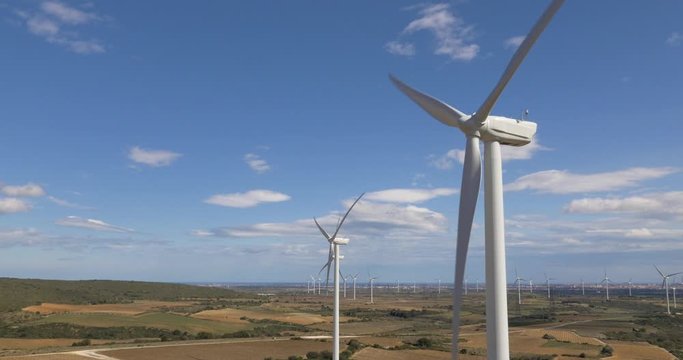 Rising up shot close to wind turbines reveals large on land wind farm